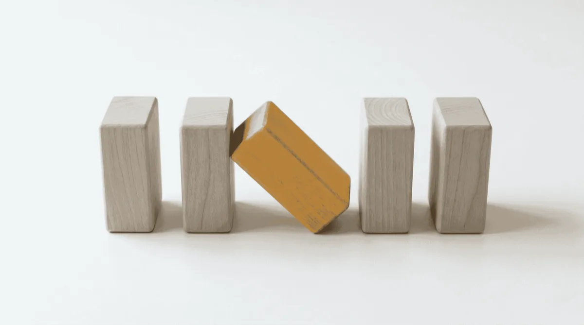 Five wooden blocks with one tipped over — common mistakes SMEs make when buying AI customer service