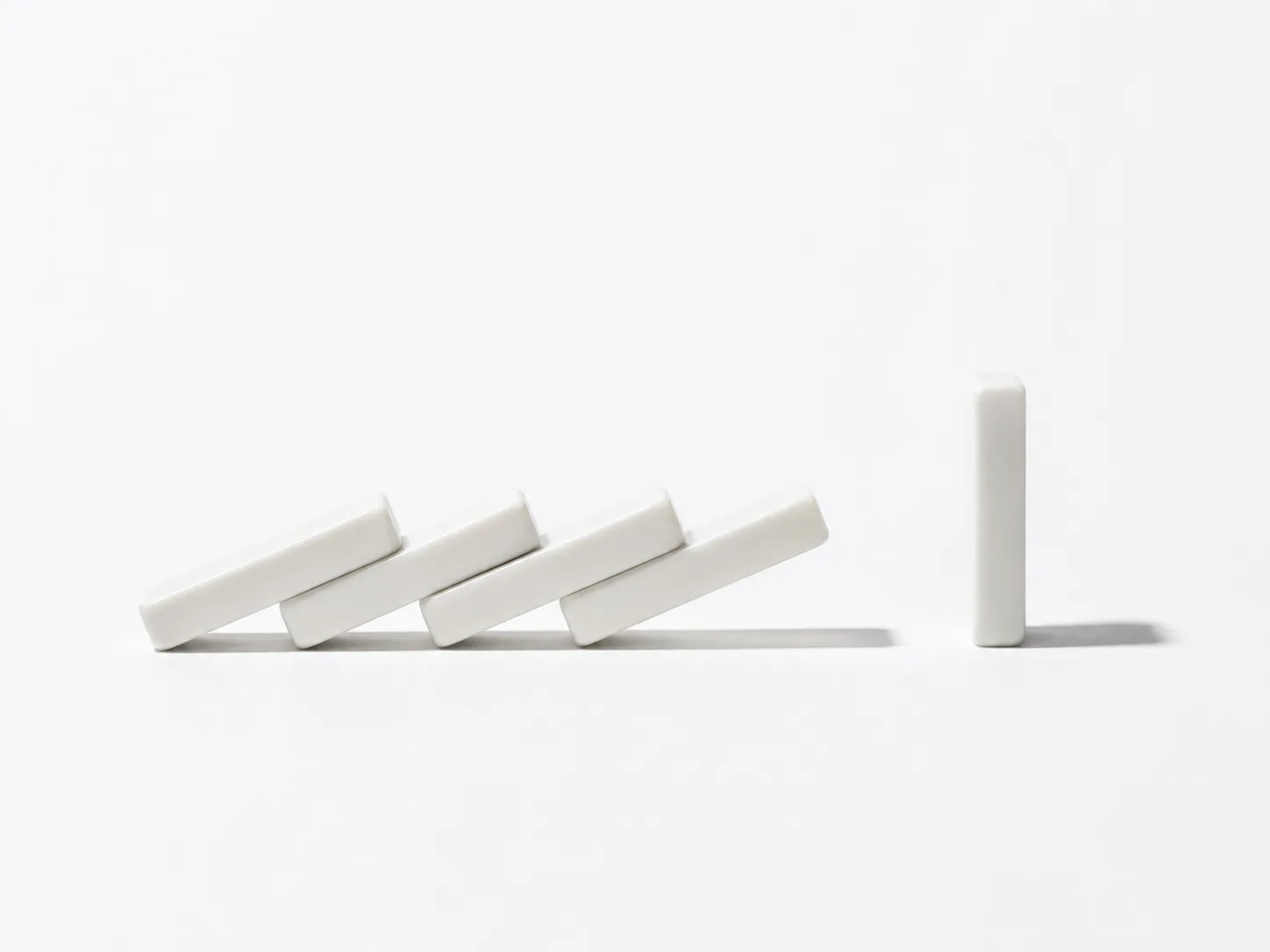 Single standing domino among several fallen ones on a white surface — why AI projects fail and how small businesses can succeed